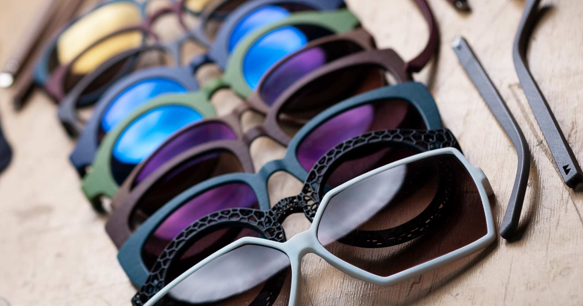 3D-gedruckte Brillenfassungen von WALLENFELS EYEWEAR in verschiedenen Farben auf einer Werkbank